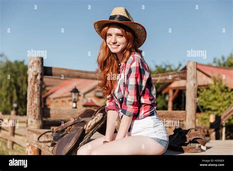 Cheerful Cute Redhead Cowgirl Sitting And Resting On The Ranch Fence