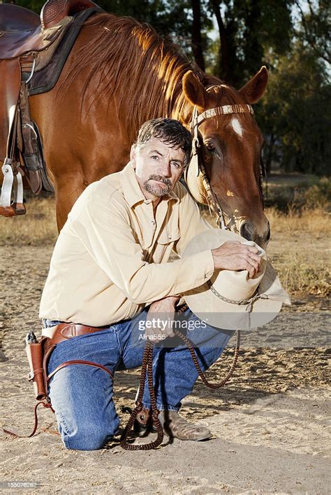 Portrait Of A Cowboy Kneeling By His Horse High Res Stock Photo Getty