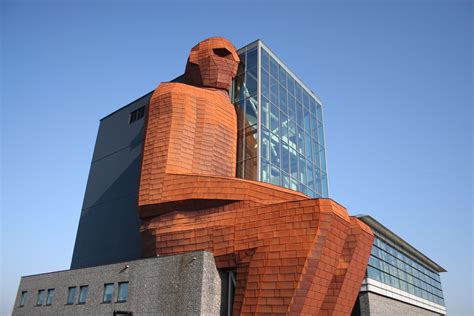 A Large Brick Building With A Giant Statue In Front Of It