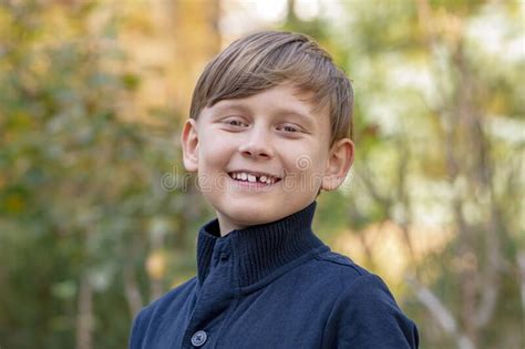 Street Portrait Of A Smiling 10 Year Old Boy On A Blurry Background Of