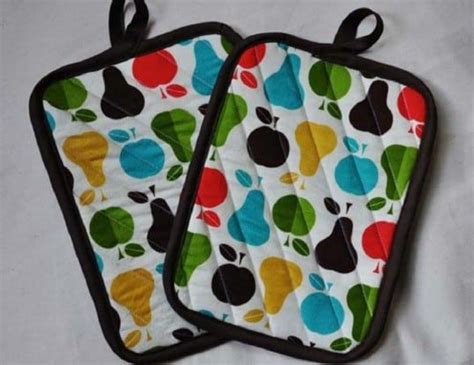 Two Oven Mitts With Apples Pears And Leaves Printed On Them Sitting On