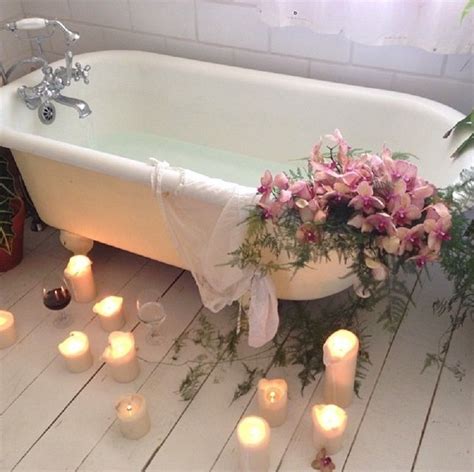 A Bath Tub Filled With Lots Of Candles Next To Potted Plants And