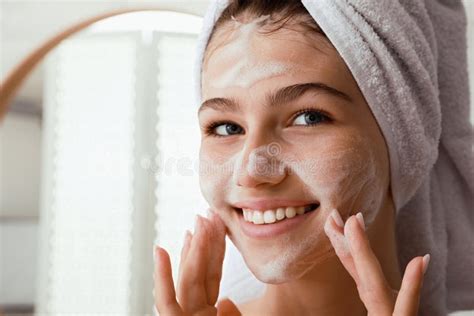 Beautiful Teenage Girl Applying Cleansing Foam Onto Face In Bathroom Closeup Skin Care