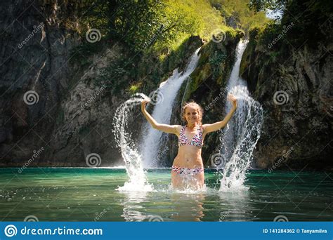 Young White Woman In A Swimsuit Splashing Water In A