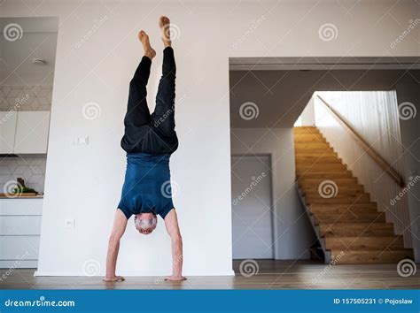 A Senior Man Indoors At Home Doing Handstand Exercise Indoors Stock