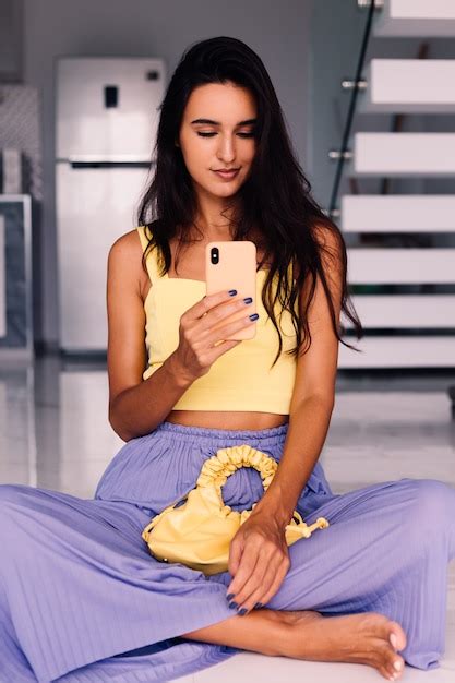 Mulher bonita blogueira de moda vestindo blusa amarela e calça roxa Foto Grátis