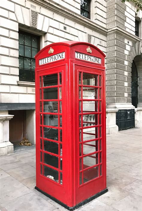 A Red Telephone Booth In Front Of A Stone Building Stock Photo Image