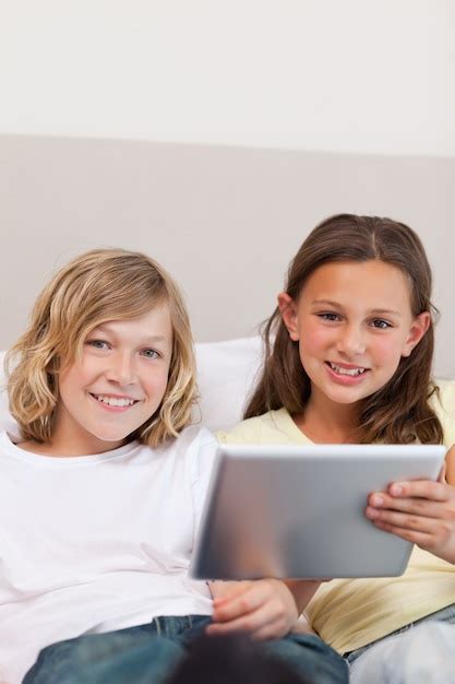 Premium Photo Brother And Sister Using Tablet On Couch