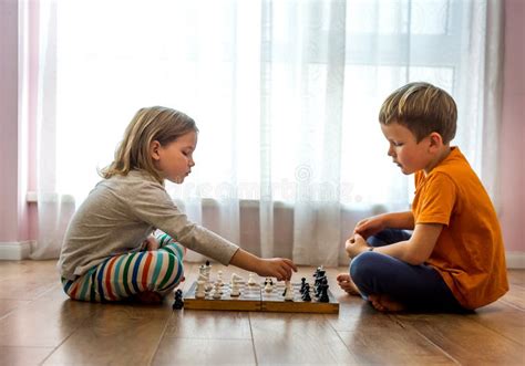 Two Cute Children Playing Chess At Home Or Kindergarten Table Game