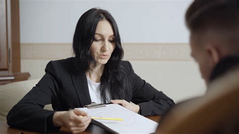 Female Caucasian Psychologist Showing Sad Face On Paper And Talking To Blurred Man In Office