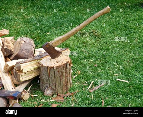A Lumberjack Axe In A Chopping Block With Split Firewood Around It