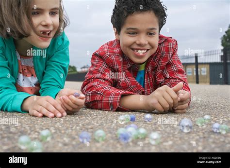 Boy And Girl 7 9 Playing Marbles Lying In Playground Stock Photo Alamy
