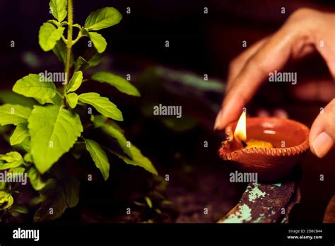 Woman Or Female Hand Holding Diya And Giving Or Putting It Near Sacred