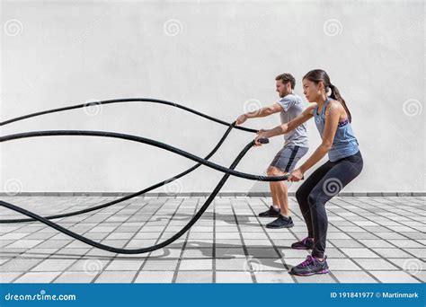 Fitness People Exercising With Battle Ropes At Gym Woman And Man