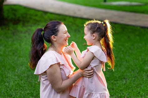 Mother And Daughter 56 Years Old Sit In The Park On The Grass In The Summer And Laugh