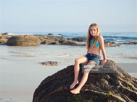 Little Girl Sitting On A Beach Rock High Res Stock Photo