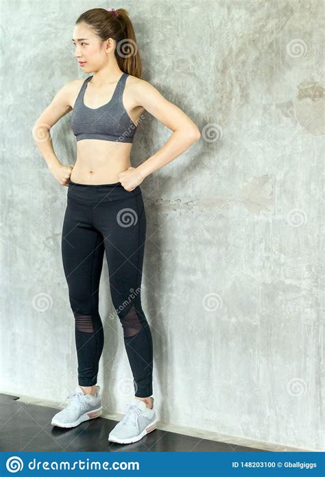Strong Asian Women Posture Standing And Lifting Up Her Arms And Exercises Muscle At Gym Stock
