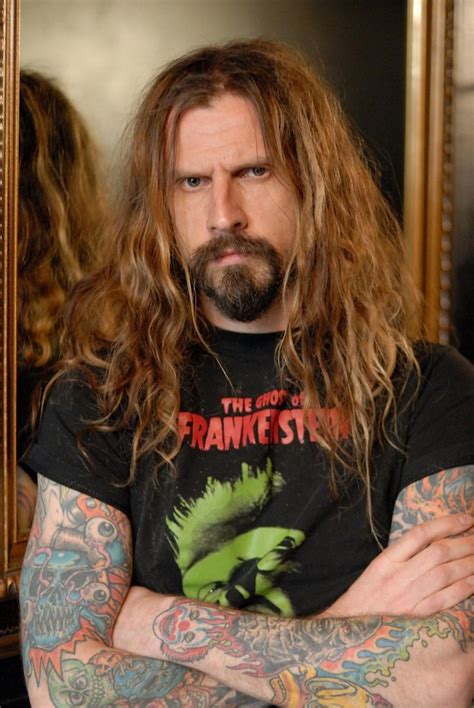 A Man With Long Hair And Tattoos Standing In Front Of A Mirror