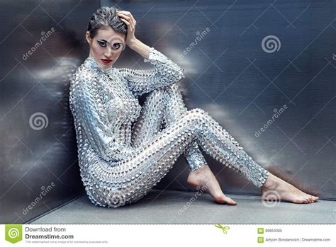 Young Cyber Woman In Silver Futuristic Costume Sitting In
