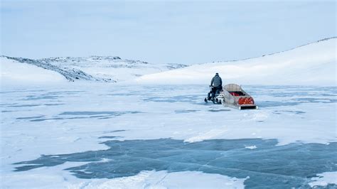 Snowmobiling Over Arctic Ocean And Frozen Tundra In Nunavut Voyageur