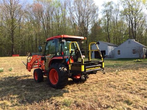 A Tractor Parked In The Middle Of A Field With Trees Behind It And A