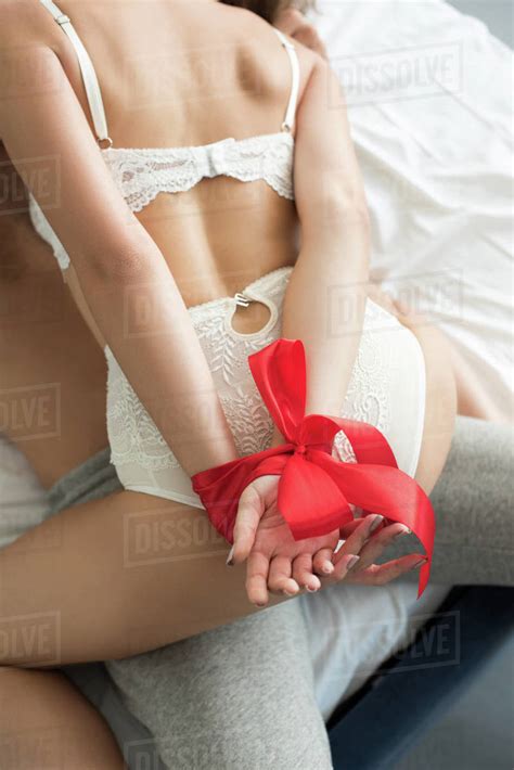 Cropped Shot Of Girl In Lingerie With Hands Tied With Red Ribbon Lying