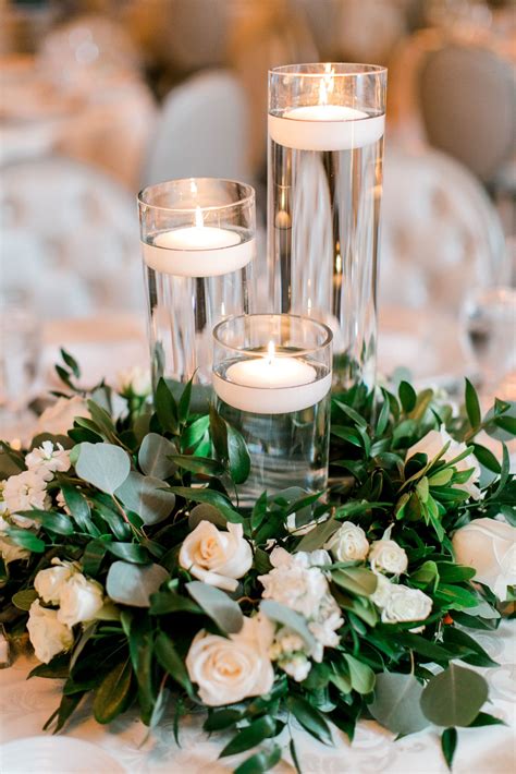 The Centerpiece Is Surrounded By Candles And Greenery With White Roses