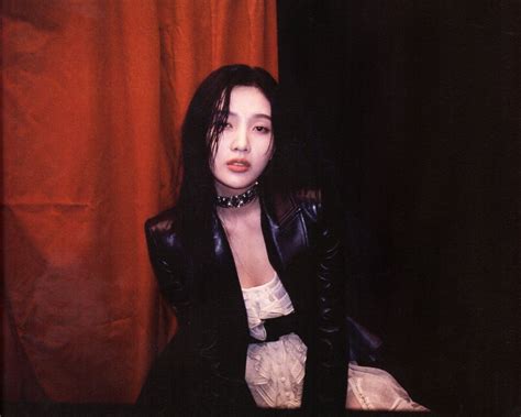 A Woman With Long Black Hair Sitting On A Chair In Front Of A Red Curtain