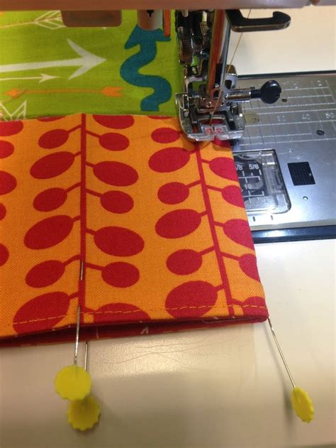 The Sewing Machine Is Working On An Orange And Green Fabric With Yellow