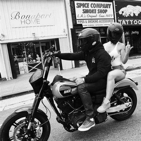 A Man Riding On The Back Of A Motorcycle With A Woman Sitting On His Seat