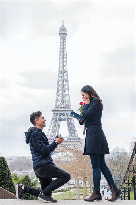 a man kneeling down next to a woman in front of the eiffel tower