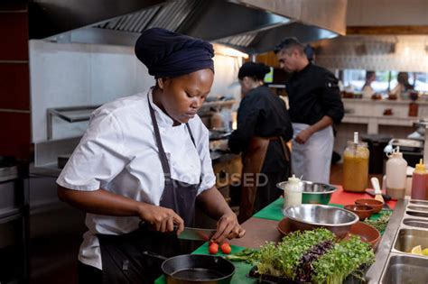 Side View Close Up Of A Young African American Female Chef Chopping Vegetables In A Restaurant