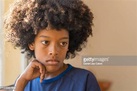 Young Boy Pondering With Hand On Chin Photos And Premium High Res