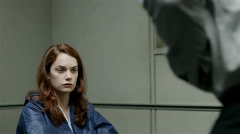 a woman sitting in front of a mirror looking at another person with red hair wearing a blue jacket