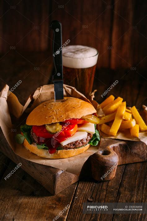 Delicious Gourmet Burger With Knife On Plate On Dark Wooden Background