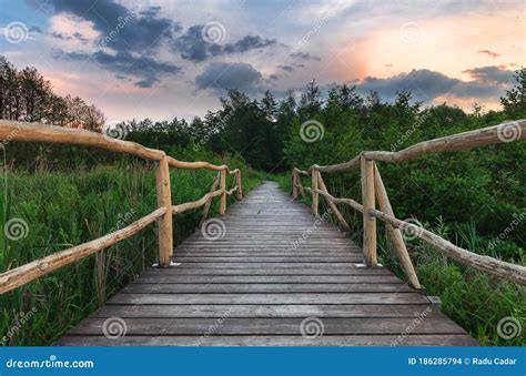 Wooden Path Bridge Over Lake At Sunset After The Storm Stock Photo