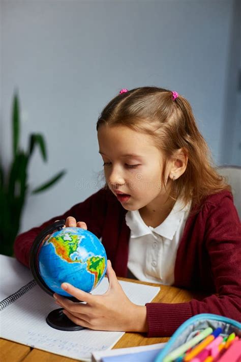 Happy Schoolgirl At Workplace Studying Globe In Classroom Stock Photo