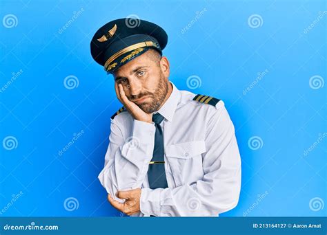 Handsome Man With Beard Wearing Airplane Pilot Uniform Thinking Looking