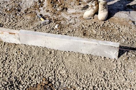 Builder Placing Edging Pin Kerb On Semi Dry Concrete Using A String