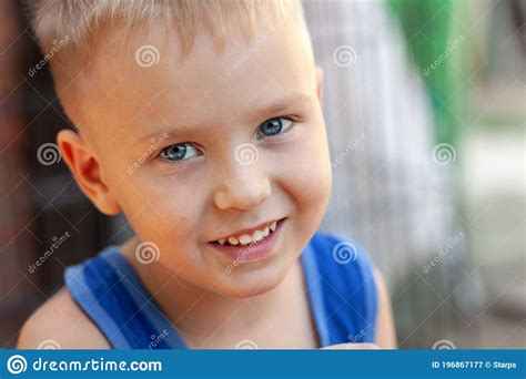 Close Up Portrait Of Cute Little Caucasian Boy With Blond Hair And Blue