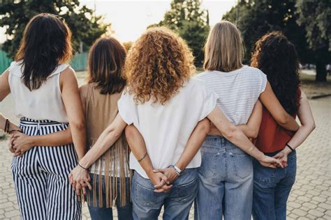 Group Of Women Friends Holding Hands Together Against Sunset