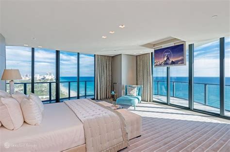 A Bedroom With Large Windows Overlooking The Ocean