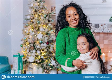 Mom And Daughter Hug Standing Against Christmas Tree Stock Image
