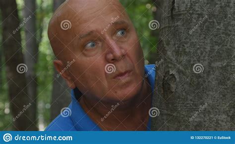 Man Looking Scared With Terrified Eyes Is Hiding After A Tree In The ...