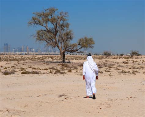Arab Man In The Desert And Looks At The City Of Dubai Stock Image