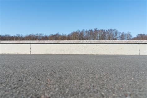 Asphalt Road With Concrete Fence Going Into The Distance With A Blurred