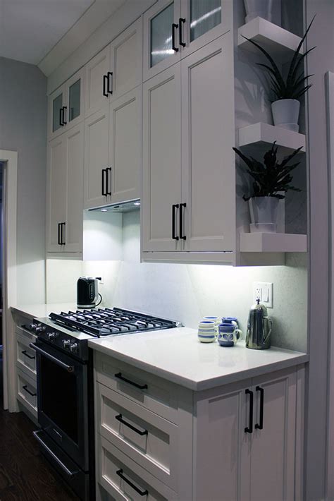 White and blue kitchen features white upper cabinets and navy blue lower cabinets adorned with aged brass pulls paired with white quartz. Modern painted white kitchen. 9 feet ceiling. Double ...