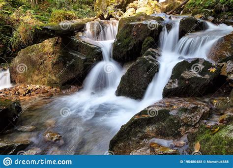 Mountain Waterfall Flows Among Green Forest And Runs Down The Beautiful