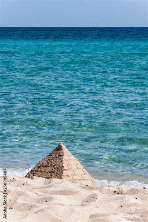 Piramide Di Sabbia Costruita Sulla Spiaggia Con Un Bel Mare Azzurro Sullo Sfondo Foto De Stock