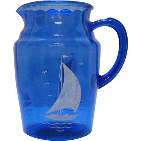 A Blue Glass Pitcher With A Sailboat Painted On It